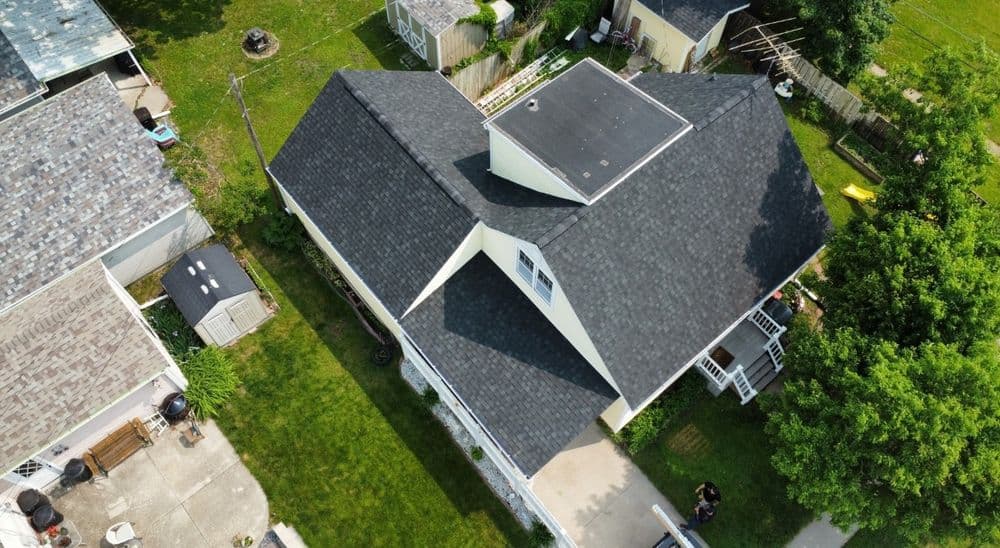 Aerial view of a residential home showcasing a modern roof and surrounding green yard.