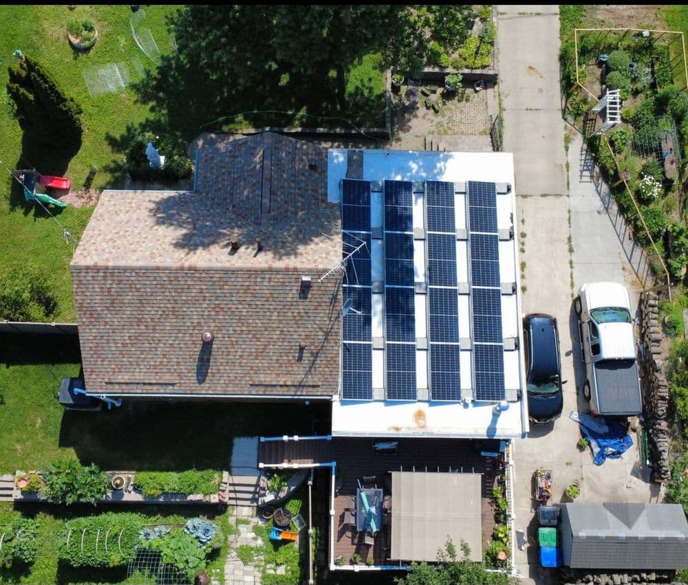 Aerial view of a house with solar panels on the roof and a garden nearby.