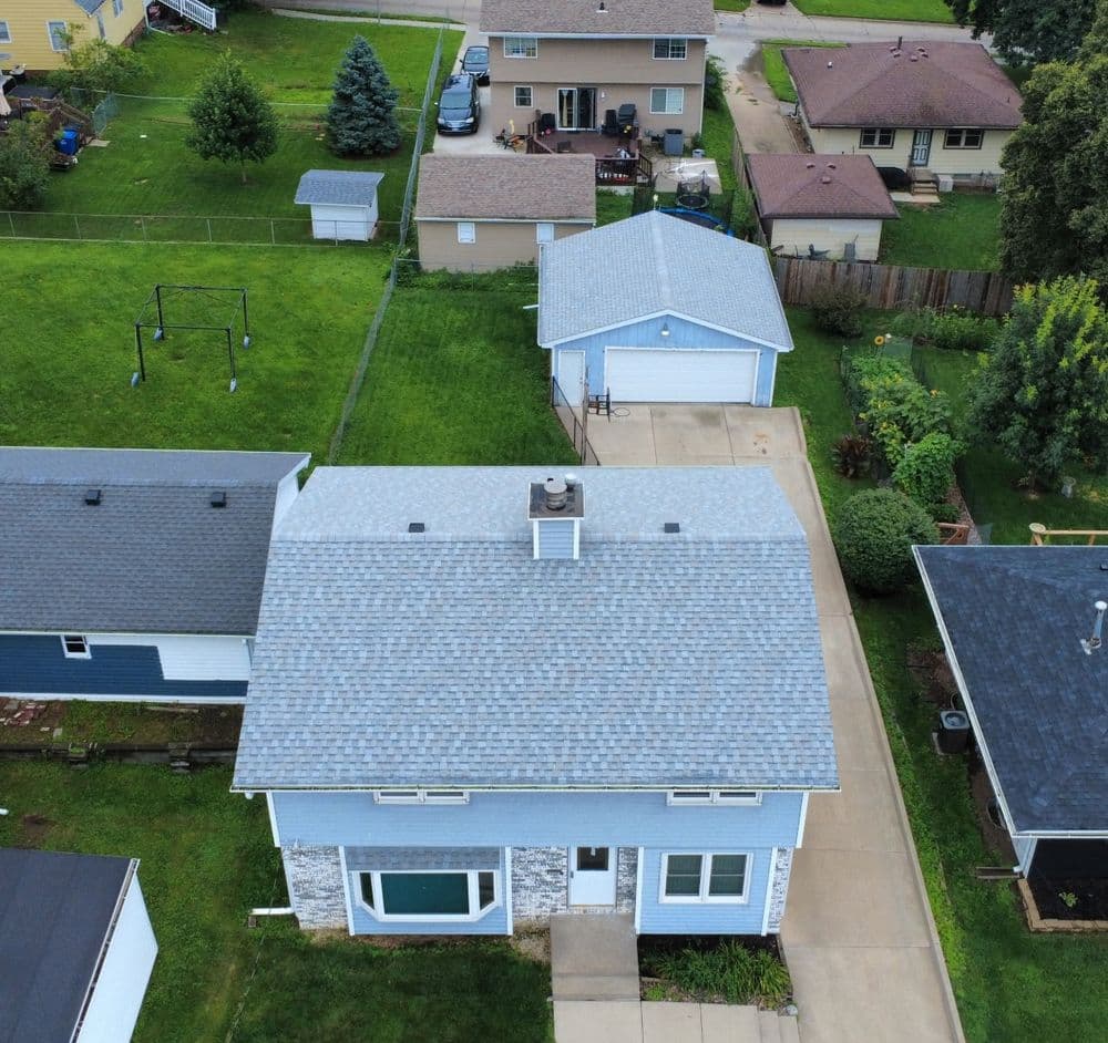 Aerial view of suburban homes with green lawns and a detached garage.