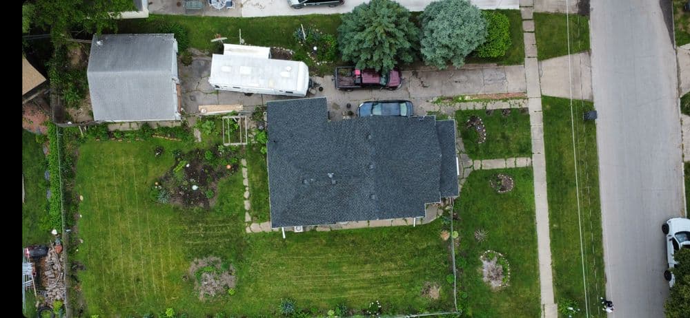Aerial view of a suburban home with a well-maintained garden and parked vehicles.