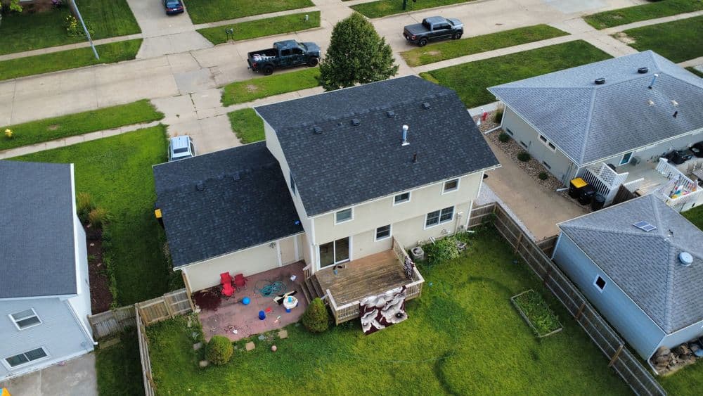 Aerial view of suburban homes with grass lawns and outdoor furniture in the backyard.