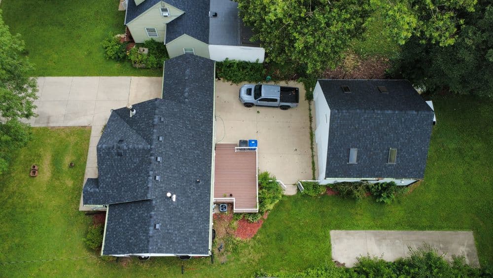 Aerial view of two homes with driveways and landscaped yards in a suburban area.
