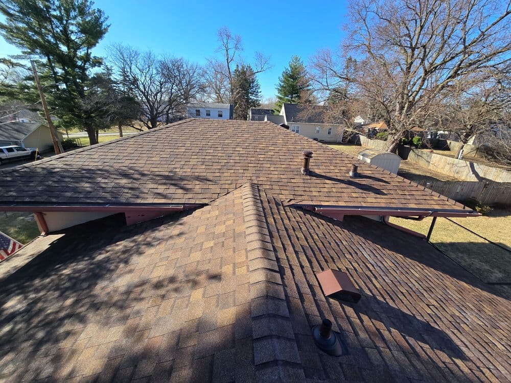 Aerial view of a residential roof showcasing shingles and surrounding trees.