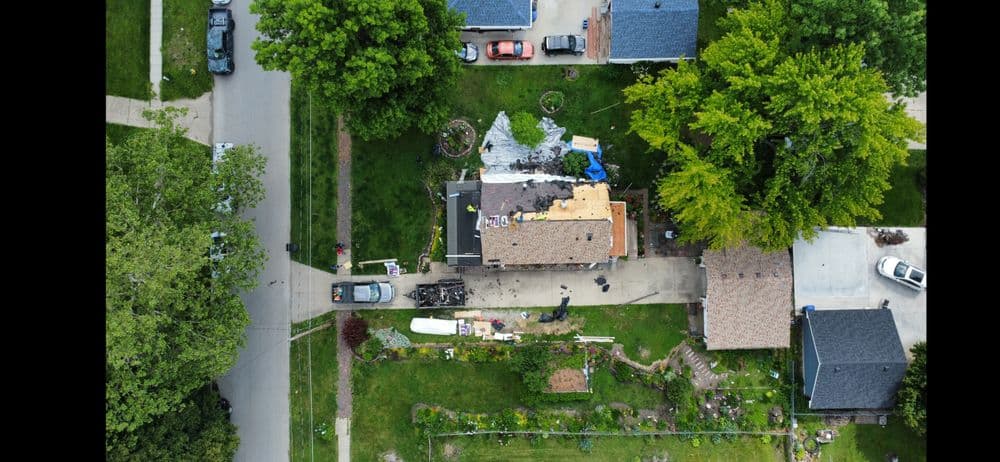 Aerial view of a residential neighborhood with a house undergoing roof repairs.